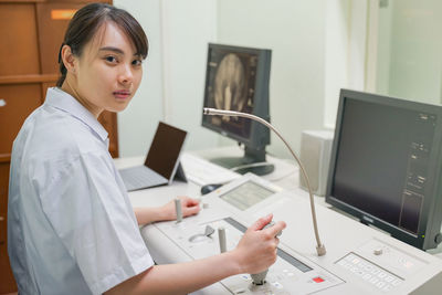 Side view of woman using mobile phone while sitting on table