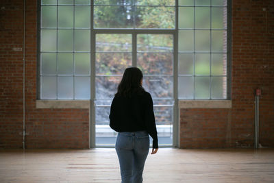 Rear view of woman standing against window