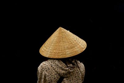 Rear view of person wearing hat against black background