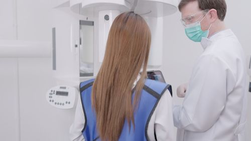 Rear view of female doctor examining patient in clinic