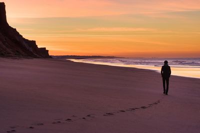 Man standing on beach against sky during sunset