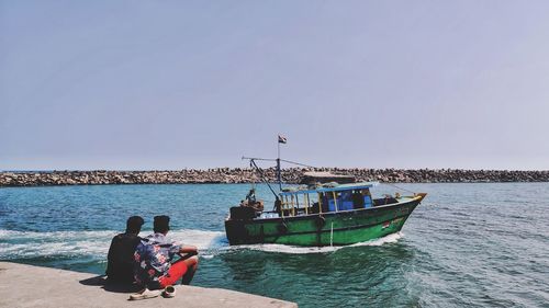 People in sea against clear sky