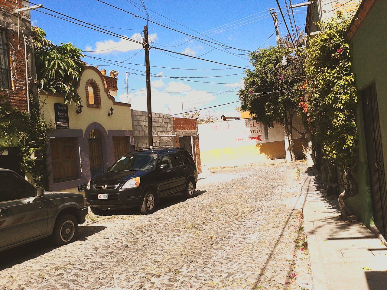 building exterior, built structure, architecture, power line, transportation, street, the way forward, electricity pylon, house, tree, clear sky, sky, sunlight, road, residential structure, car, cable, city, day, residential building