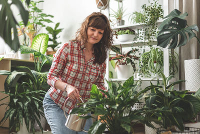 Portrait of smiling young woman standing against plants