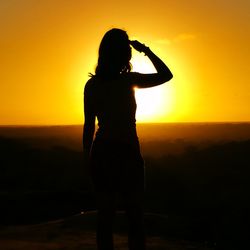 Silhouette woman standing against orange sky