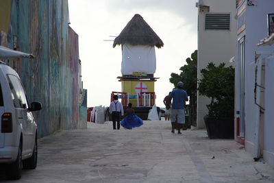 Rear view of people walking on street amidst buildings in city