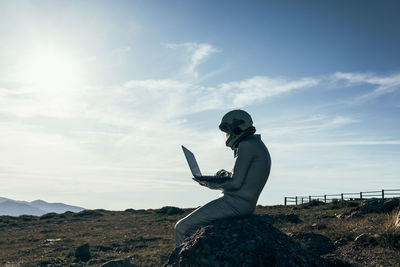 Side view of man using smart phone against sky