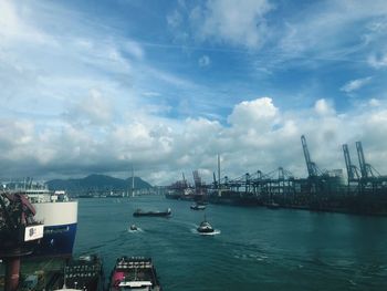 View of city at waterfront against cloudy sky