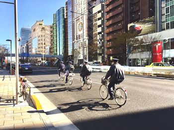 People riding bicycle on city street by buildings