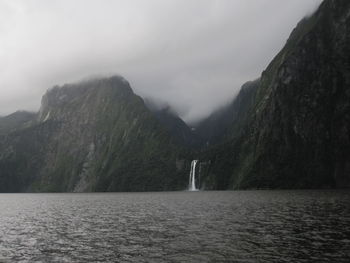 Scenic view of sea by mountains against sky