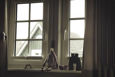 Doll sitting on window sill at home