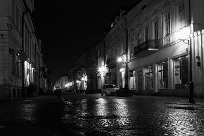 Illuminated street amidst buildings in city at night