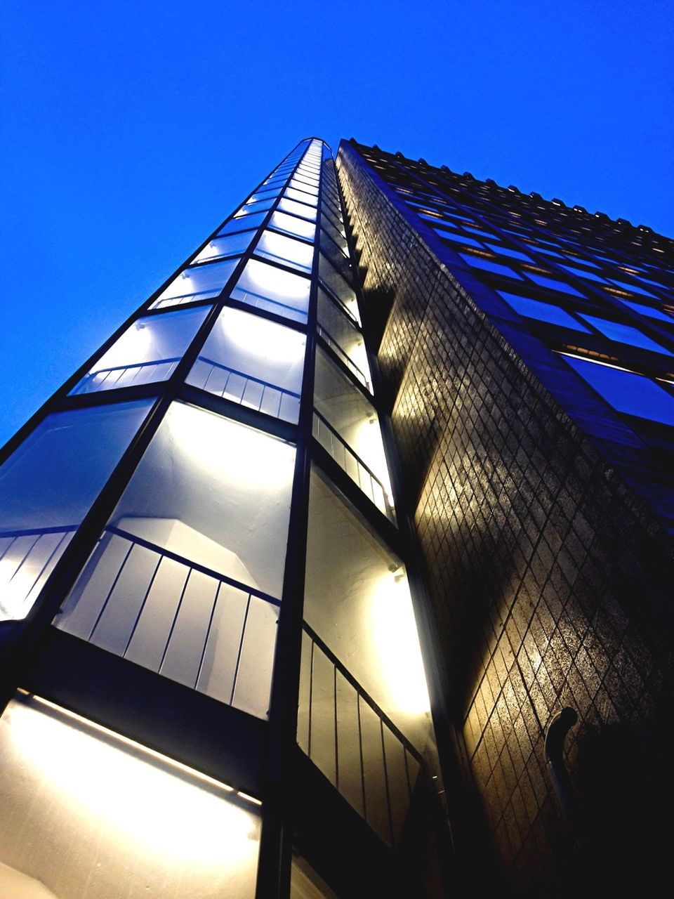 low angle view, architecture, built structure, building exterior, modern, clear sky, tall - high, office building, glass - material, skyscraper, sunlight, tower, sky, city, blue, building, sun, sunbeam, day, no people