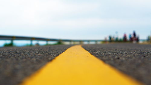 Surface level of yellow road against sky