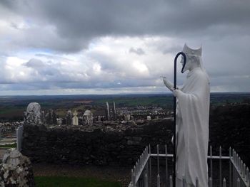 Woman in city against cloudy sky