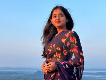 Young woman standing against sky