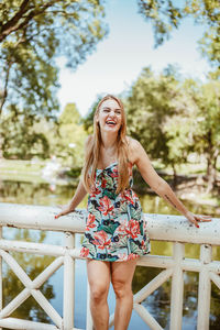 Portrait of smiling young woman standing against railing