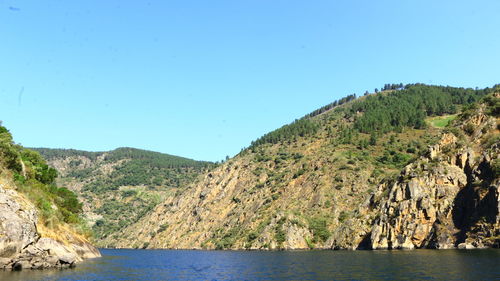 Scenic view of lake and mountains against clear blue sky