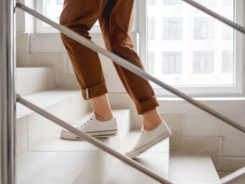 Woman in white sneakers and khaki trousers goes upstairs to her apartment.  staircase in building. 