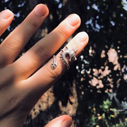 Cropped hand of woman wearing ring against trees