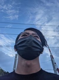 Low angle portrait of young man against sky