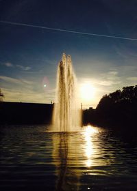 Fountain amidst river against sky on sunny day