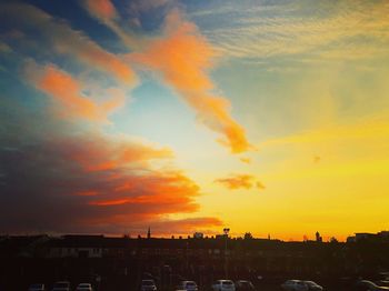 Silhouette cityscape against dramatic sky during sunset