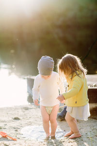 Toddlers stepping in a puddle at the beach in the sand during golden h