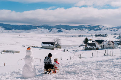 People skiing on snow covered mountain against sky