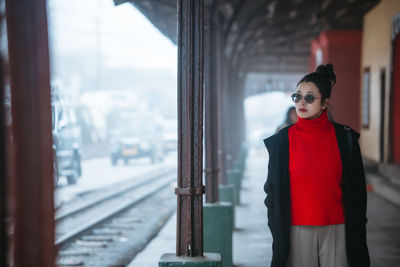 Woman wearing sunglasses standing at railroad station