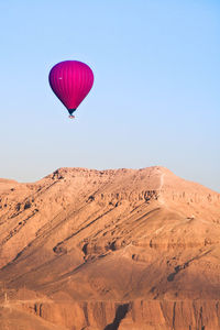 Hot air balloon in desert against clear sky