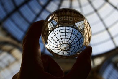 Cropped image of person holding crystal ball against monument ceiling 