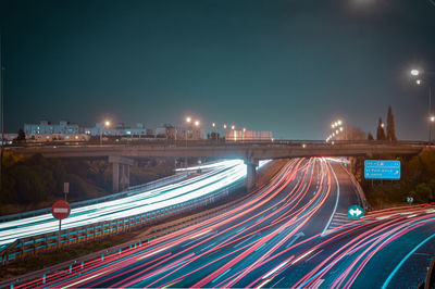 Light trails on road in city against sky at night