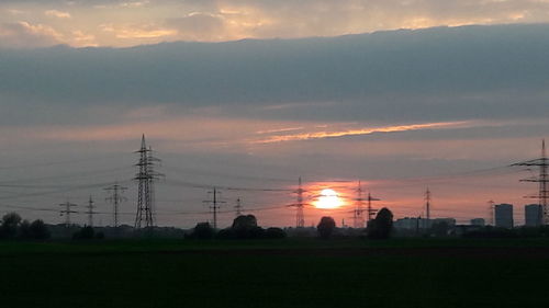 Electricity pylon on field against sky during sunset