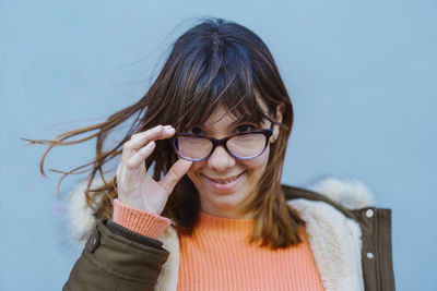 Portrait of smiling young woman against wall