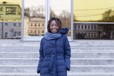 Portrait of woman standing by entrance of building