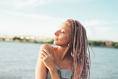 Young woman with eyes closed against sea