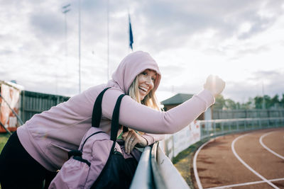 Woman stood a the side of a running track cheering her team mates on