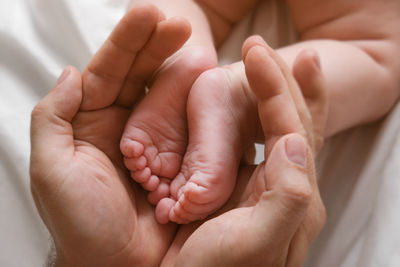 Father holding baby feet in hands. legs newborn in male parents hand. children's feet in the  palm.