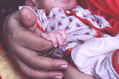 Low section of mother holding baby hand