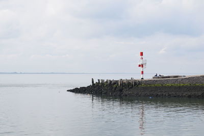 Lighthouse by sea against sky