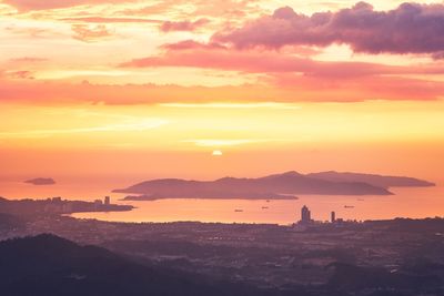 Scenic view of sea and buildings against orange sky