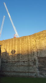 Low angle view of construction site against clear blue sky