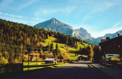 Road amidst trees and mountains against sky