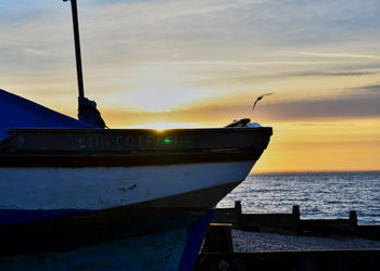 Silhouette boats moored on sea against sky during sunset