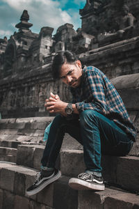 Young man sitting outside temple