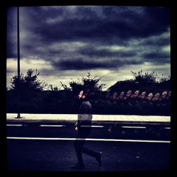 Man standing on bench in city against sky