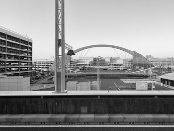 Bridge over river by buildings against clear sky