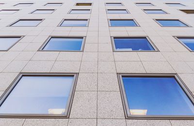 Low angle view of glass building against blue sky