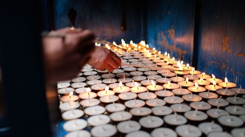 Cropped image of people burning incense with tea light candles at temple